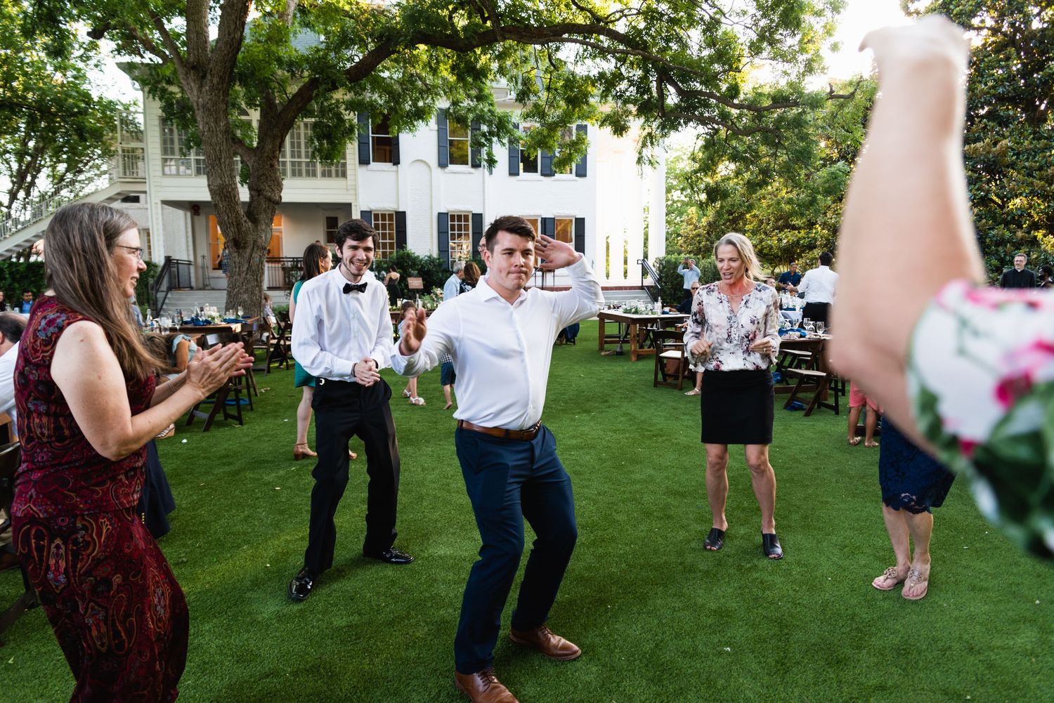 Party guests dancing together on a manicured lawn during an outdoor event.