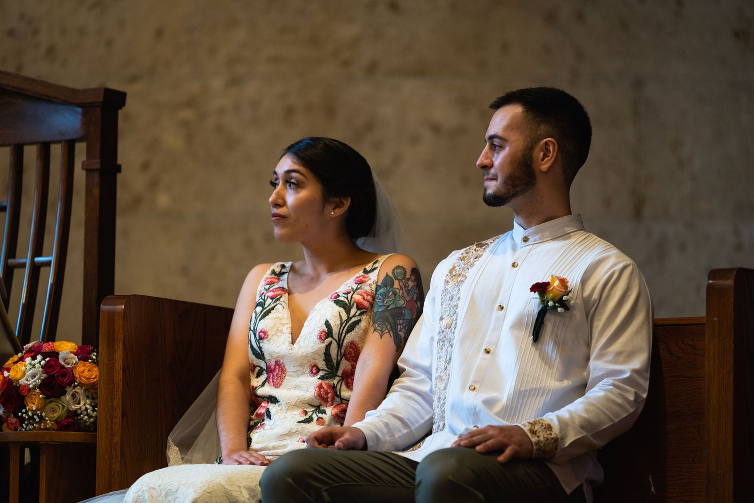 Newlyweds sit together during their ceremony in traditional attire with floral decorations.