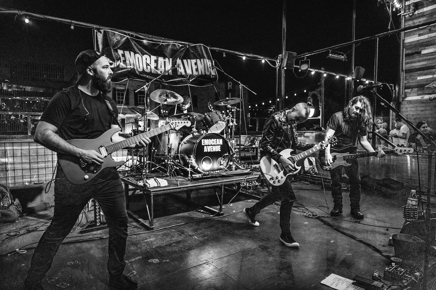 Rock band performs energetically under Endgean Avenue sign during night concert.