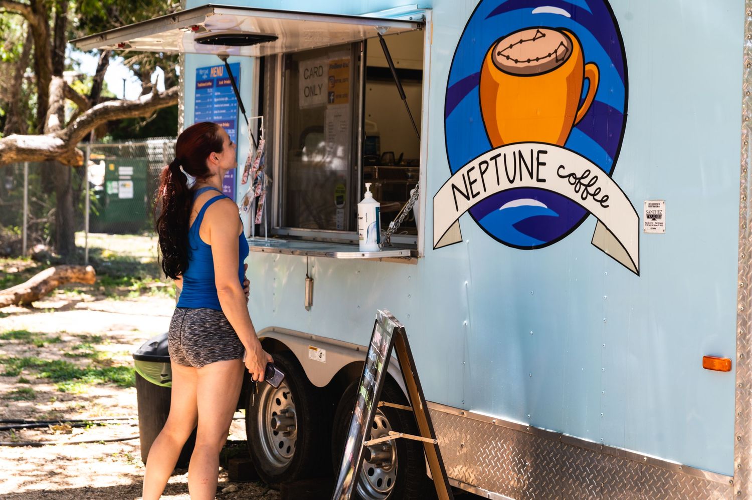 Blue food truck with coffee cup logo serving customers at outdoor event.