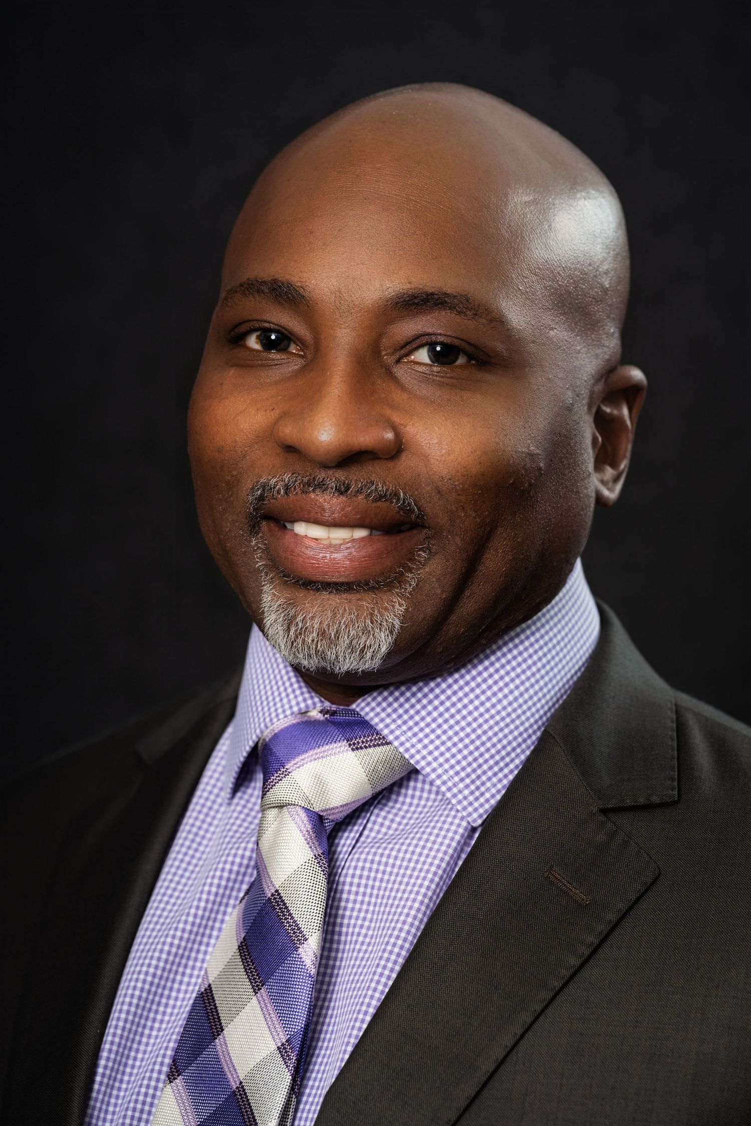 Close-up professional portrait of a person in business attire with a purple tie.