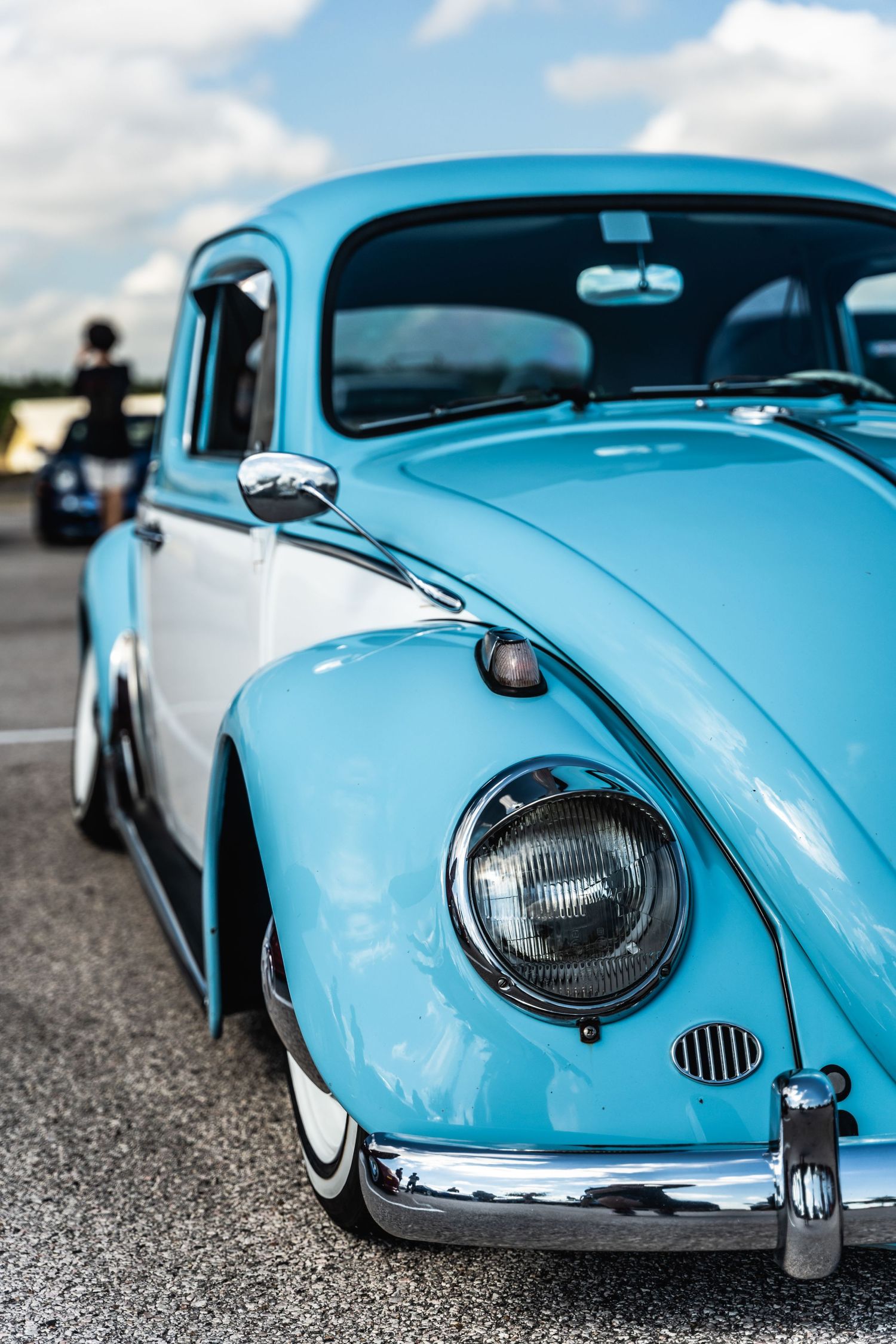 Classic light blue Volkswagen Beetle with custom lowered suspension and chrome trim.