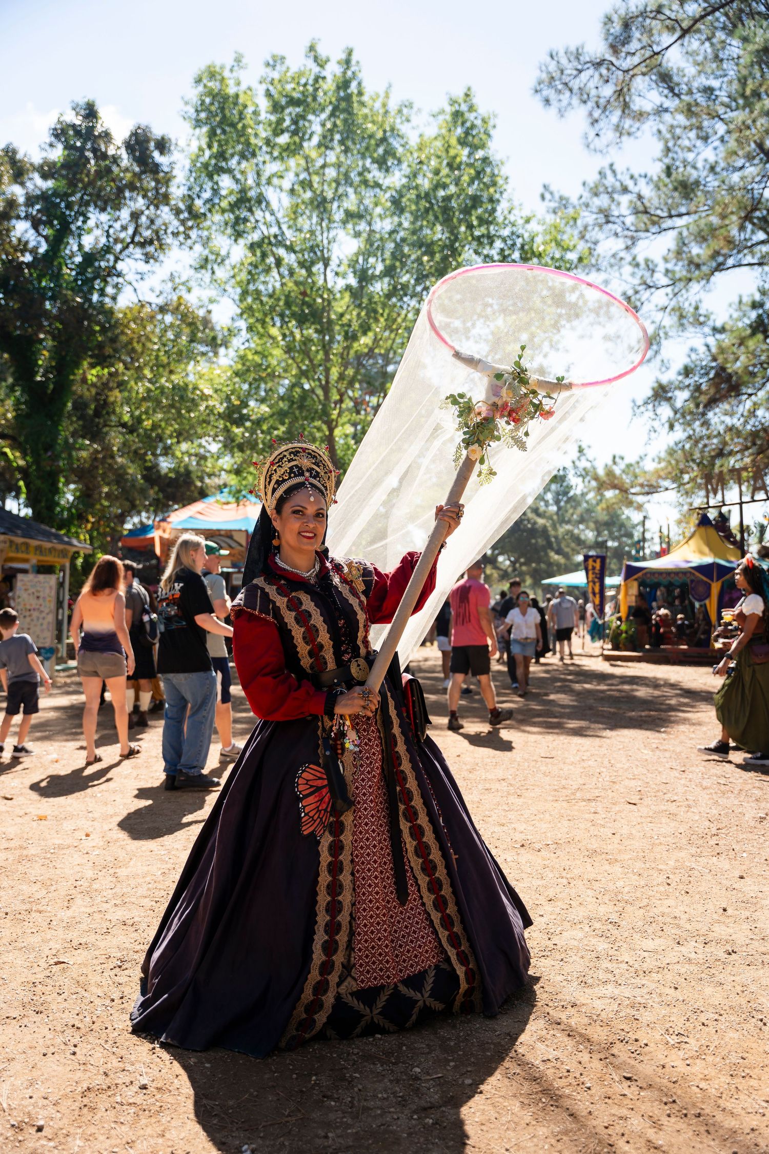 Medieval performers in ornate period costumes dance and twirl with white fabric at a Renaissance festival.