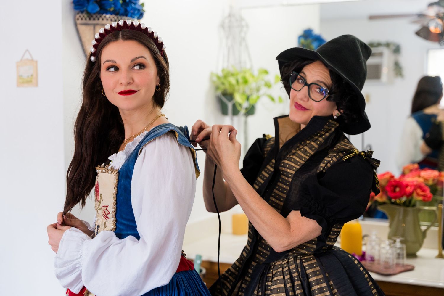 Two people in costume pose together at an event, one wearing a blue and white dress and another in black attire.