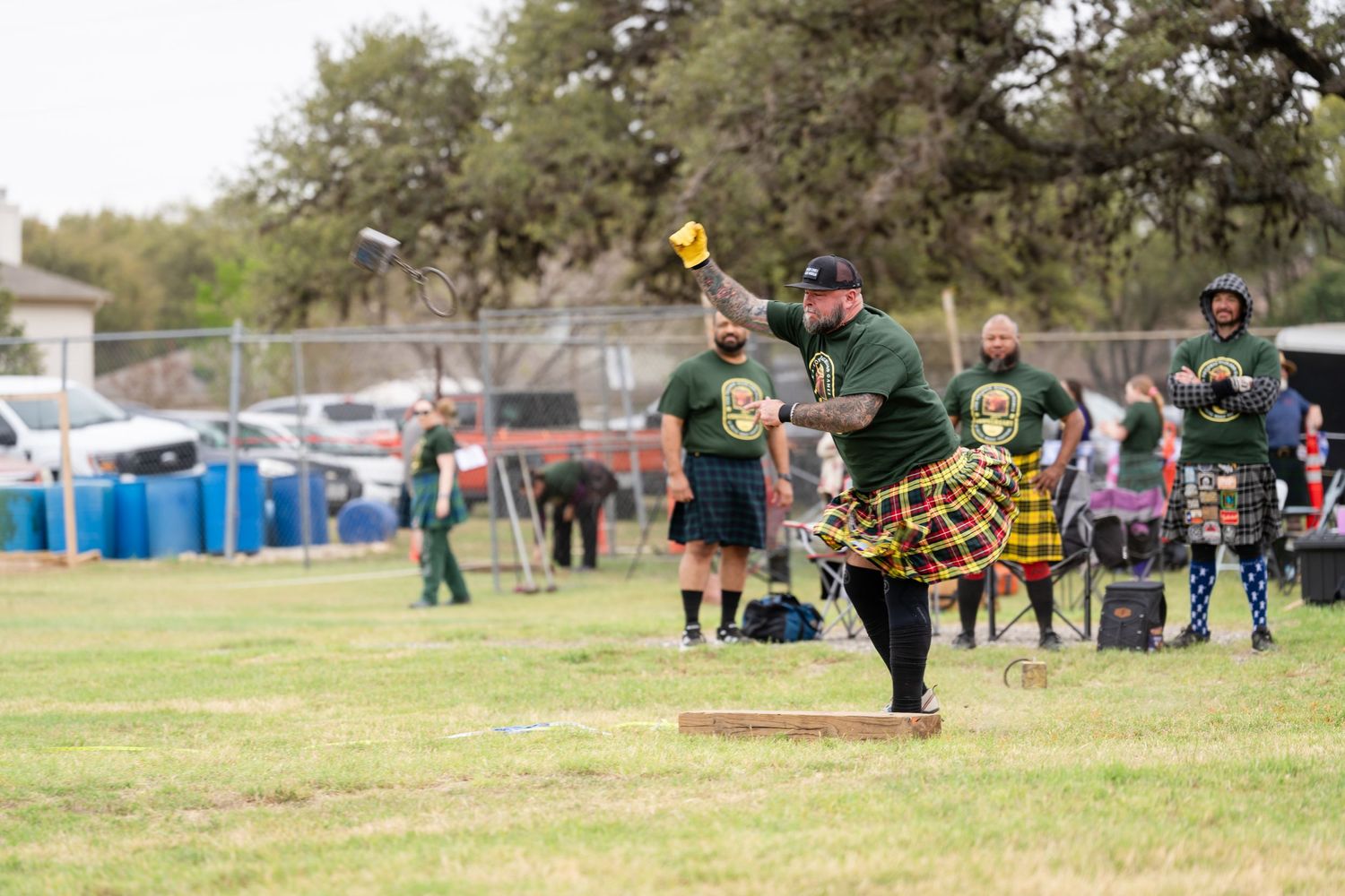 Man in green kilt competes in Highland Games throwing event at outdoor Scottish festival competition.