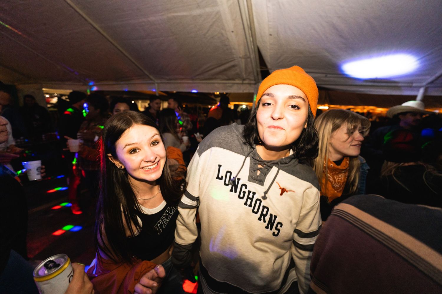 Friends posing together at a nighttime party with colorful lighting effects.