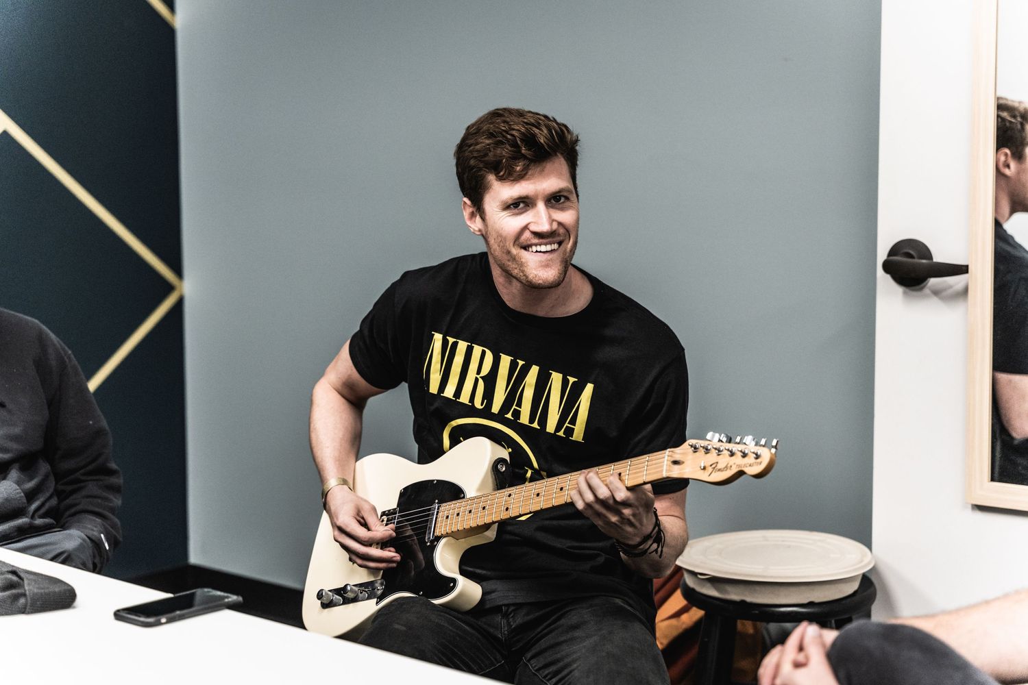 Musician in a Nirvana t-shirt playing an electric guitar in a studio setting.