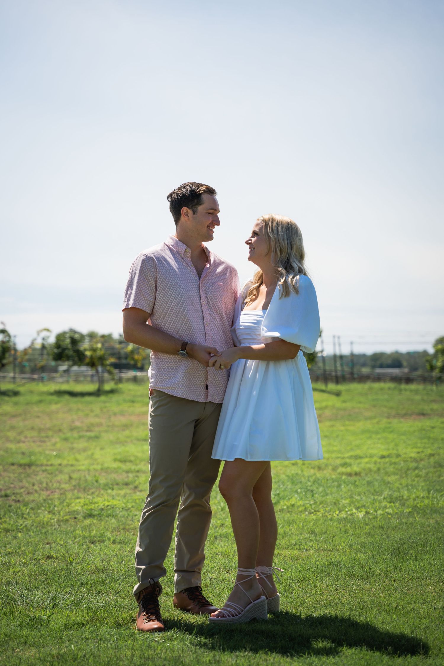A couple shares a joyful moment together in an outdoor field on a sunny day.