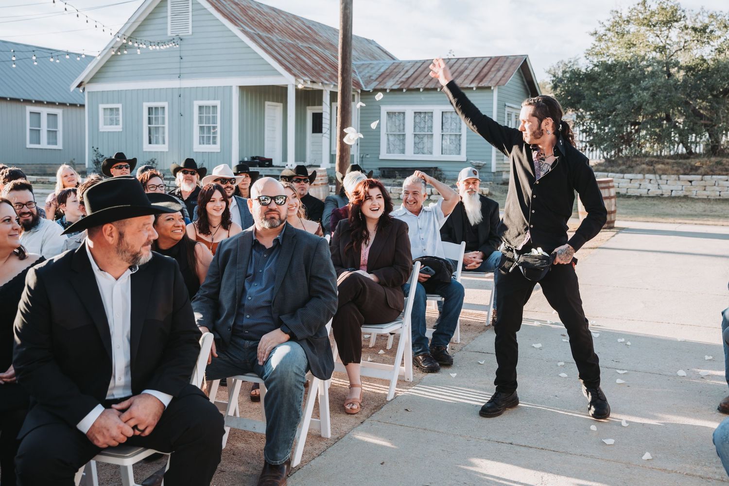 An energetic performer engages with seated audience members at an outdoor gathering.