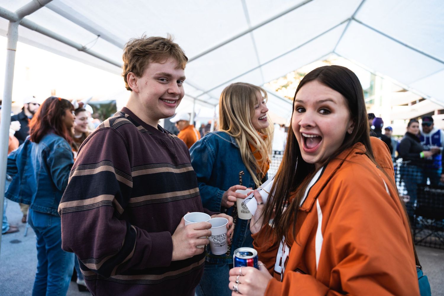 Friends laugh and socialize at an outdoor sporting event.