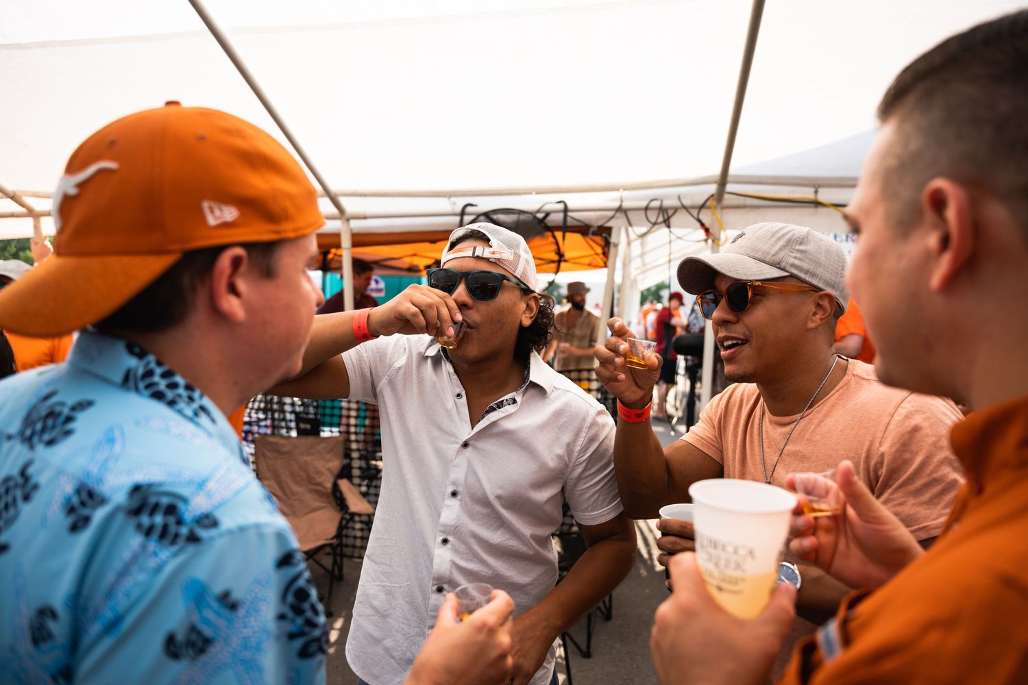 People engaged in animated conversation while holding drinks at an outdoor party.