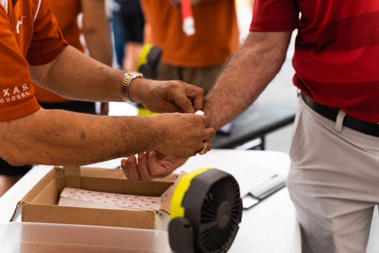 Close-up of hands exchanging items at an outdoor vendor booth.