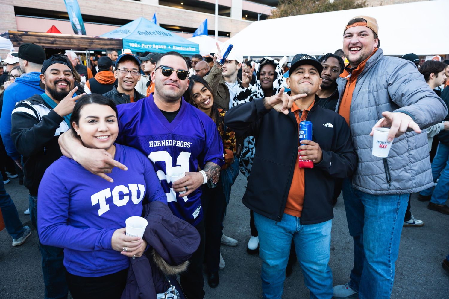 Crowd of TCU supporters wearing purple jerseys pose together at a tailgate celebration.