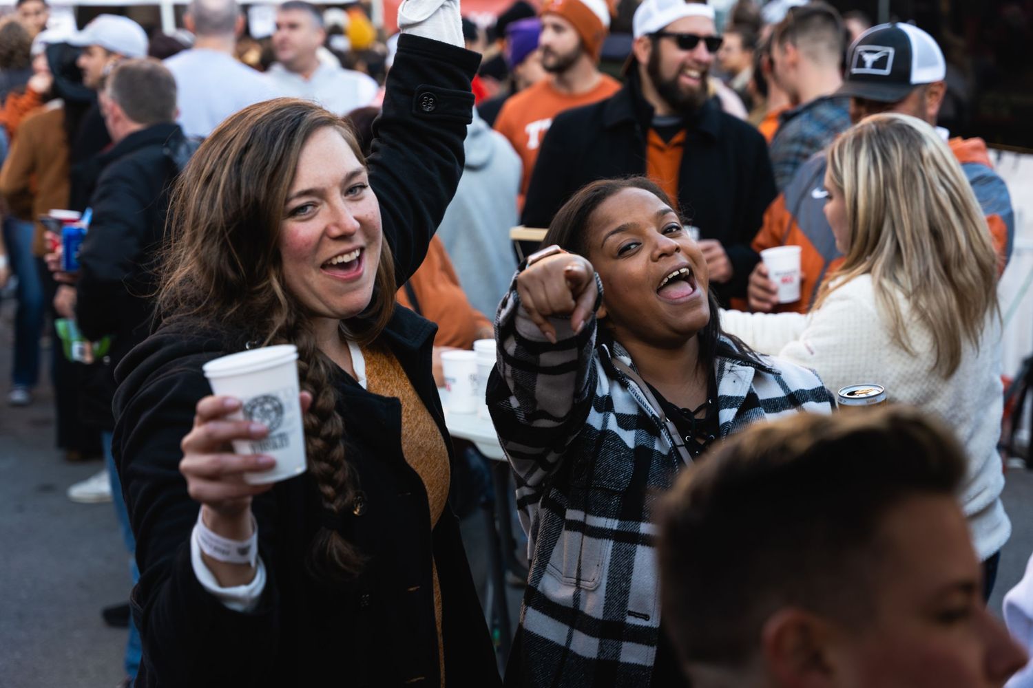 Happy attendees cheering and enjoying themselves at an outdoor celebration.
