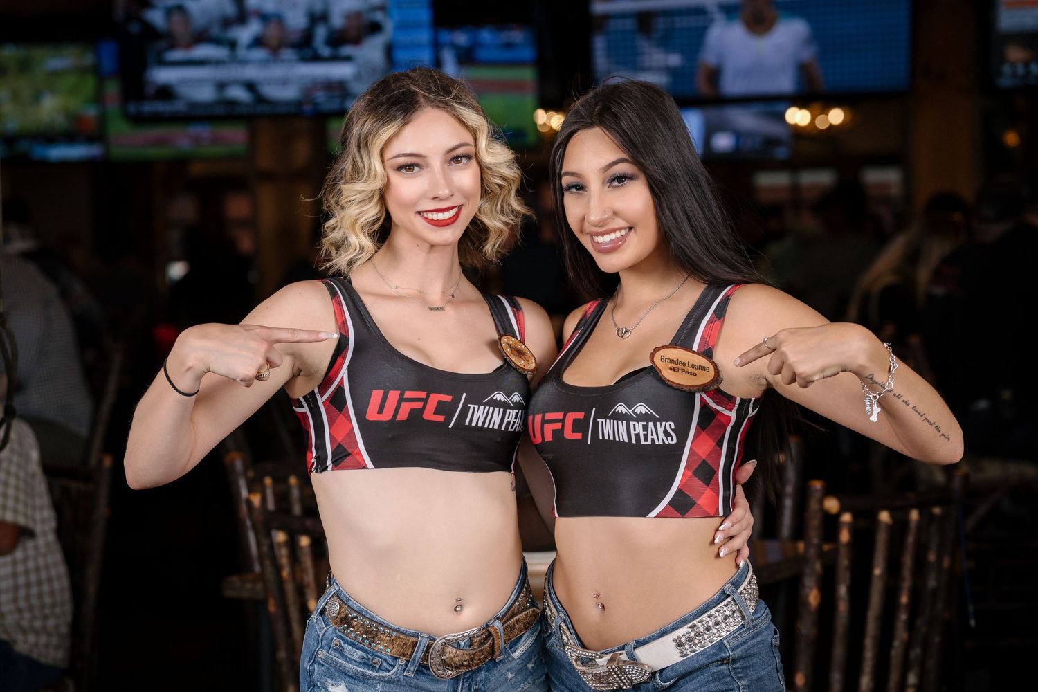 Two promotional models in UFC gear pose together showing boxing stance.