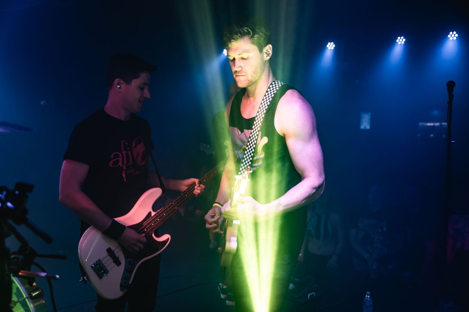 Musicians performing with vibrant green stage lighting effects.