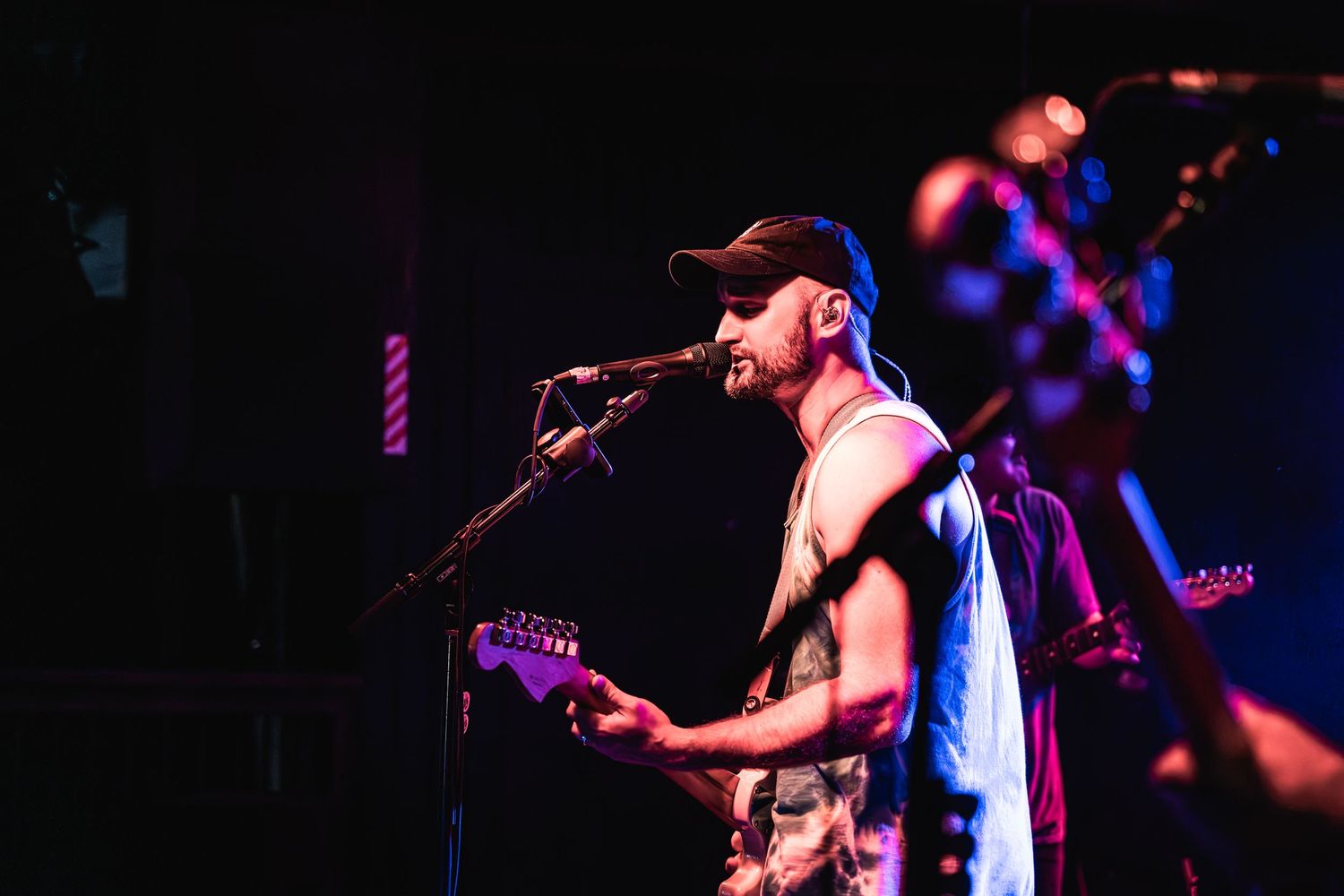 Musician performing on stage with colorful purple lighting effects.