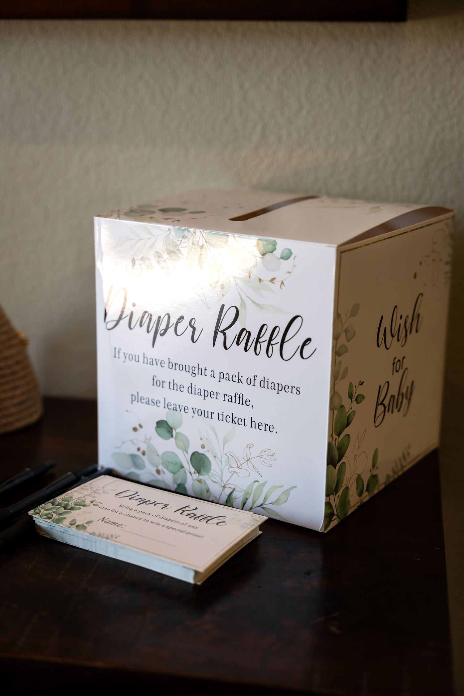 Baby shower diaper raffle box with floral design and instruction cards.