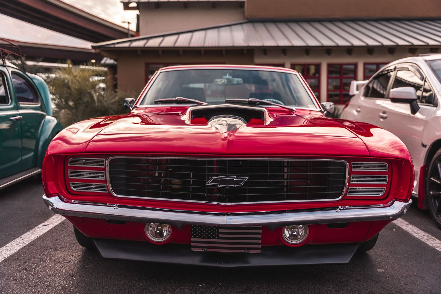 Front view of a classic red Chevrolet Camaro in a parking lot.