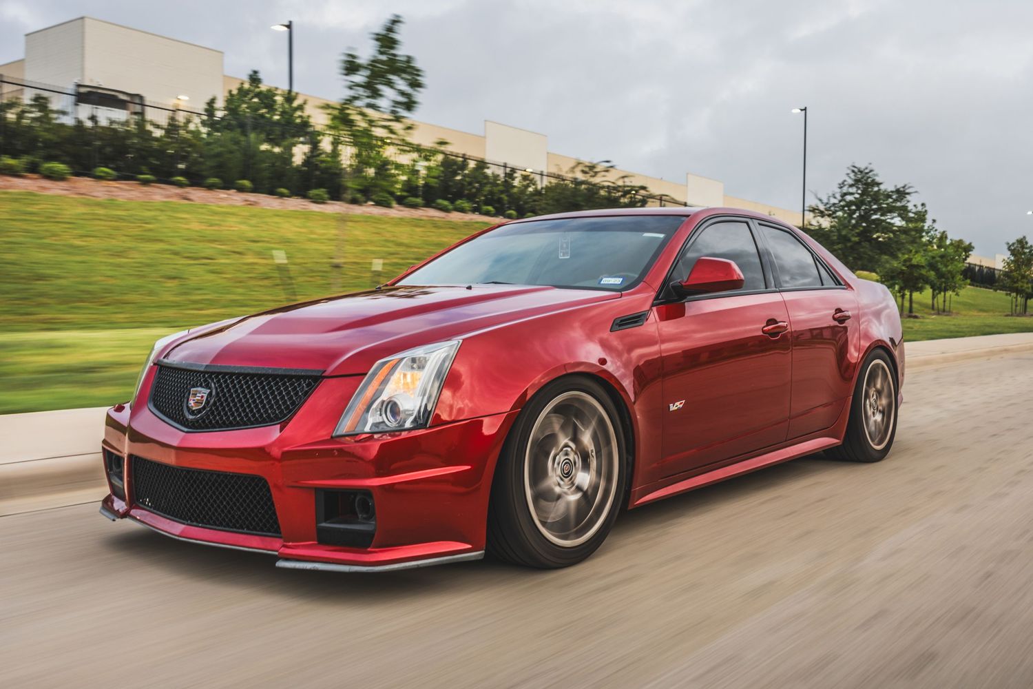 Red Cadillac CTS-V sport sedan showcasing aggressive styling while driving on street.
