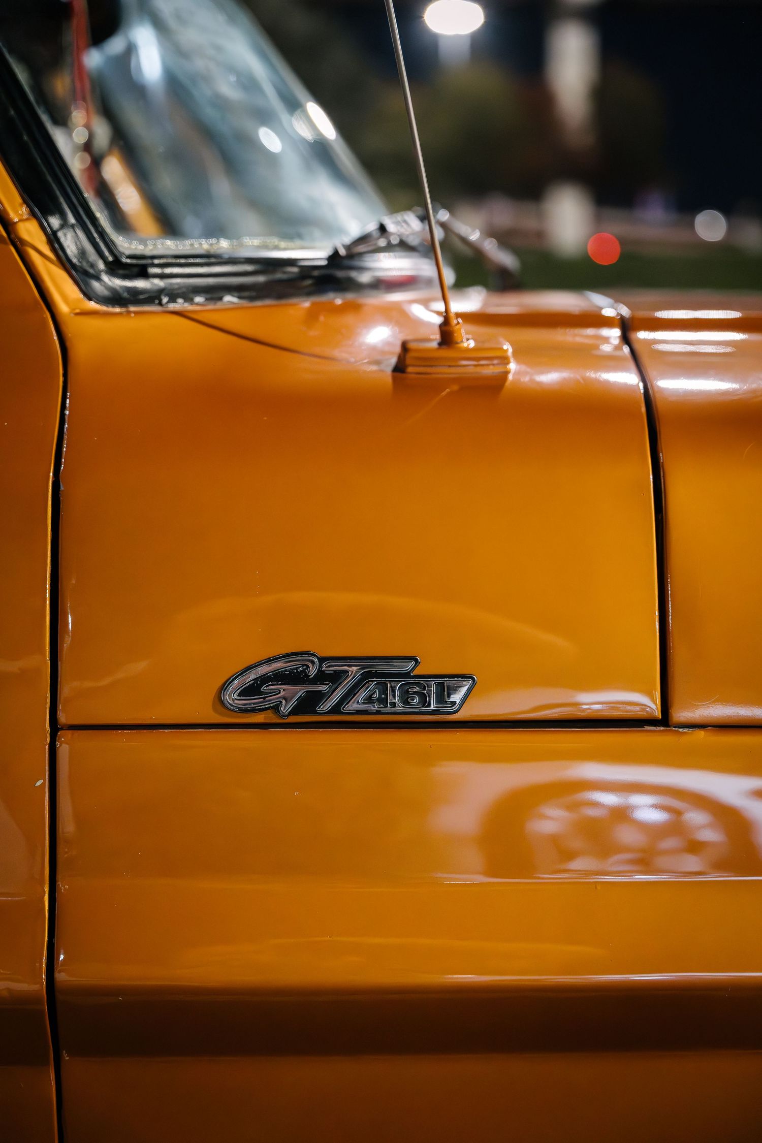 Close-up detail shot of orange vintage Ford C7 truck badge on fender.