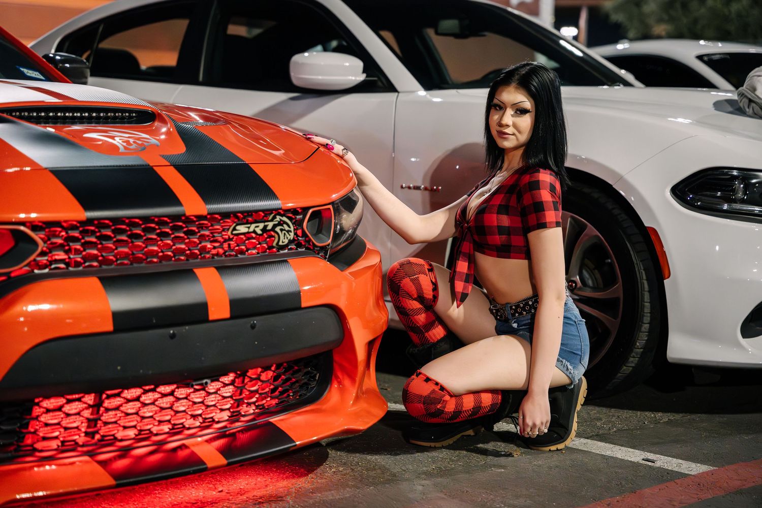 Orange custom sports car with racing stripes displayed at outdoor car show.