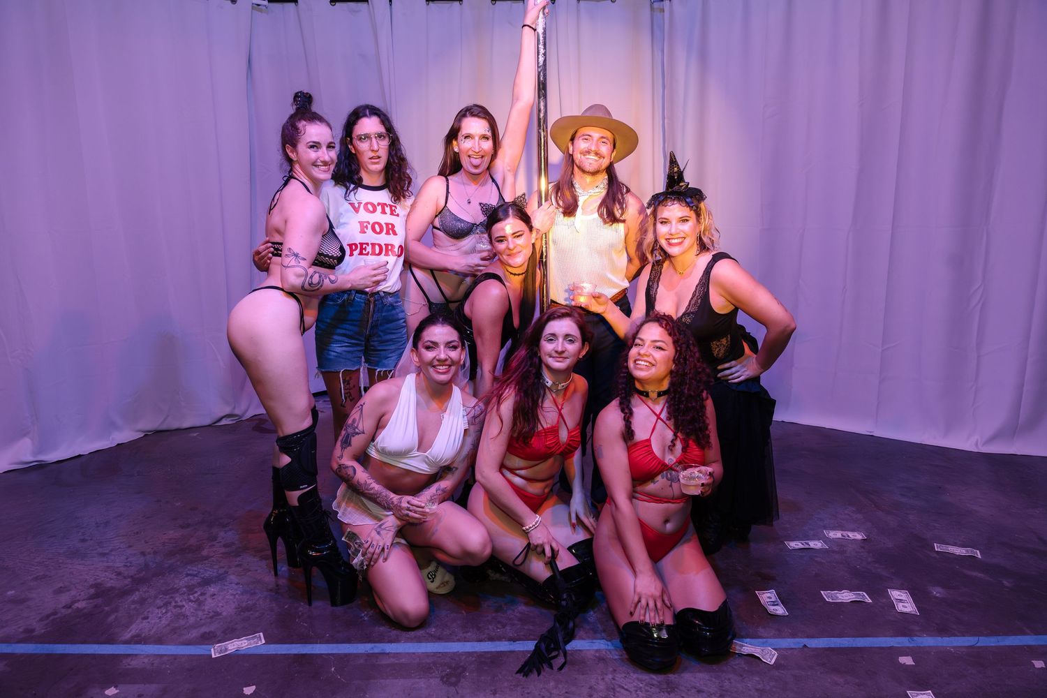 Performance troupe gathered for a group photo in theatrical lighting.