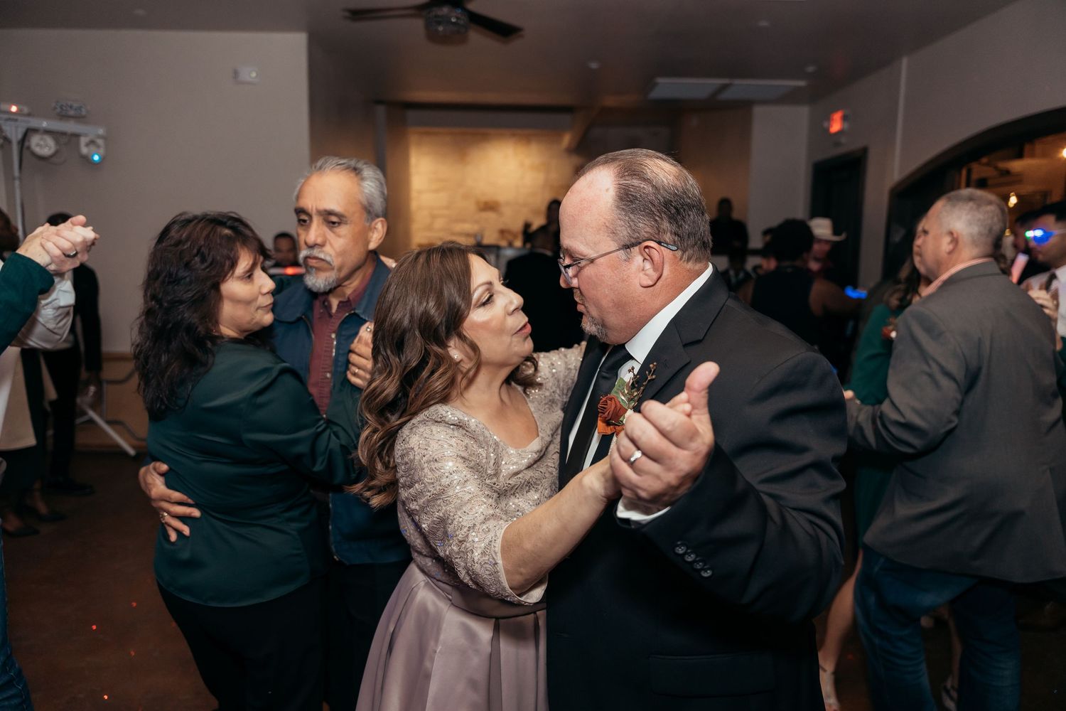 Wedding reception guests dancing together on the dance floor under indoor lighting.