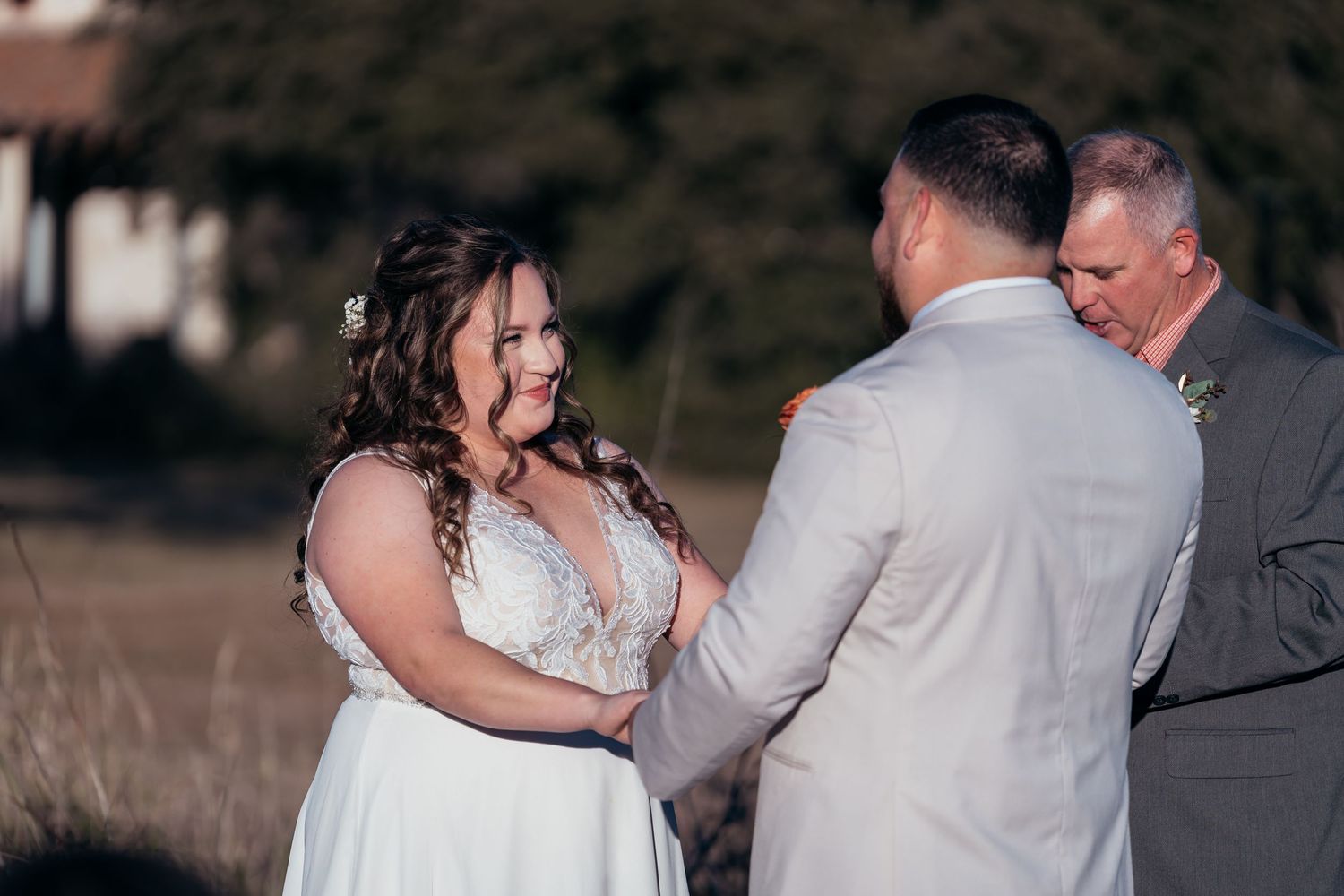Sweet exchange between couple during sunlit outdoor wedding ceremony.