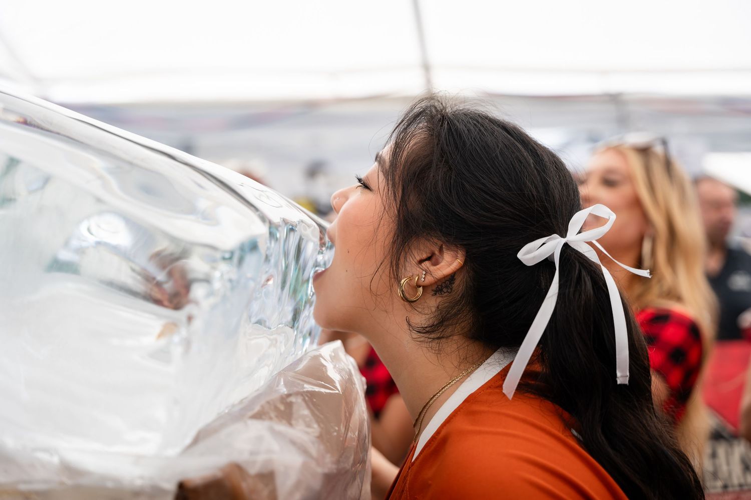 Attendee drinking from a large container at an outdoor festival.