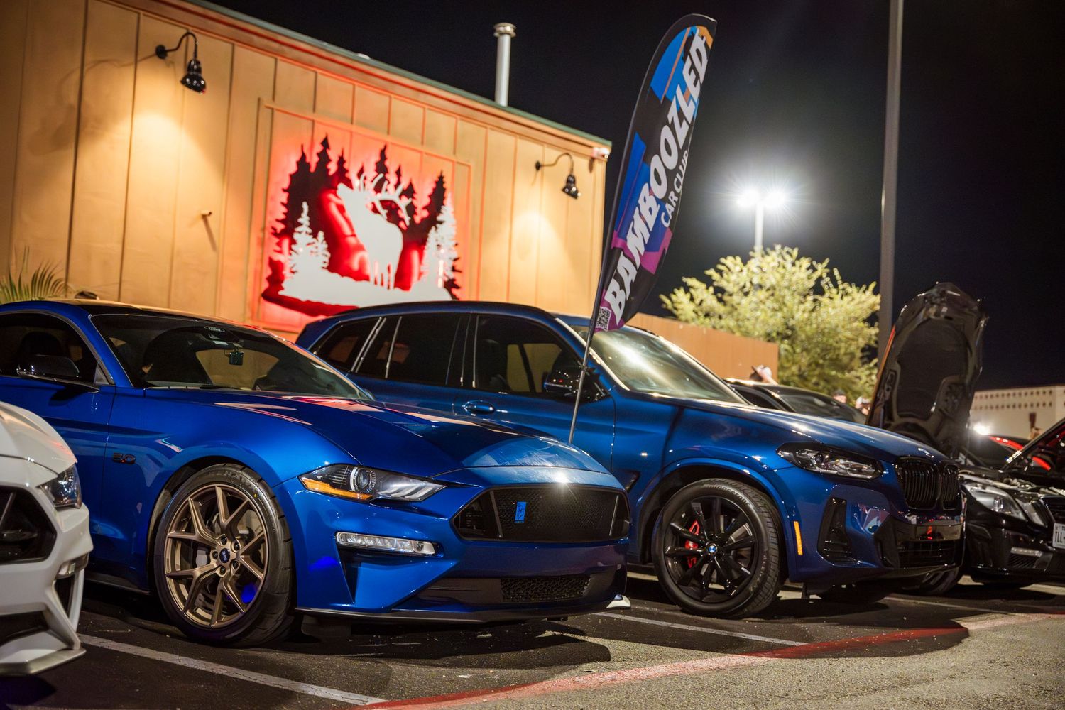 Modified blue sports car with custom wheels parked at a nighttime car meet.