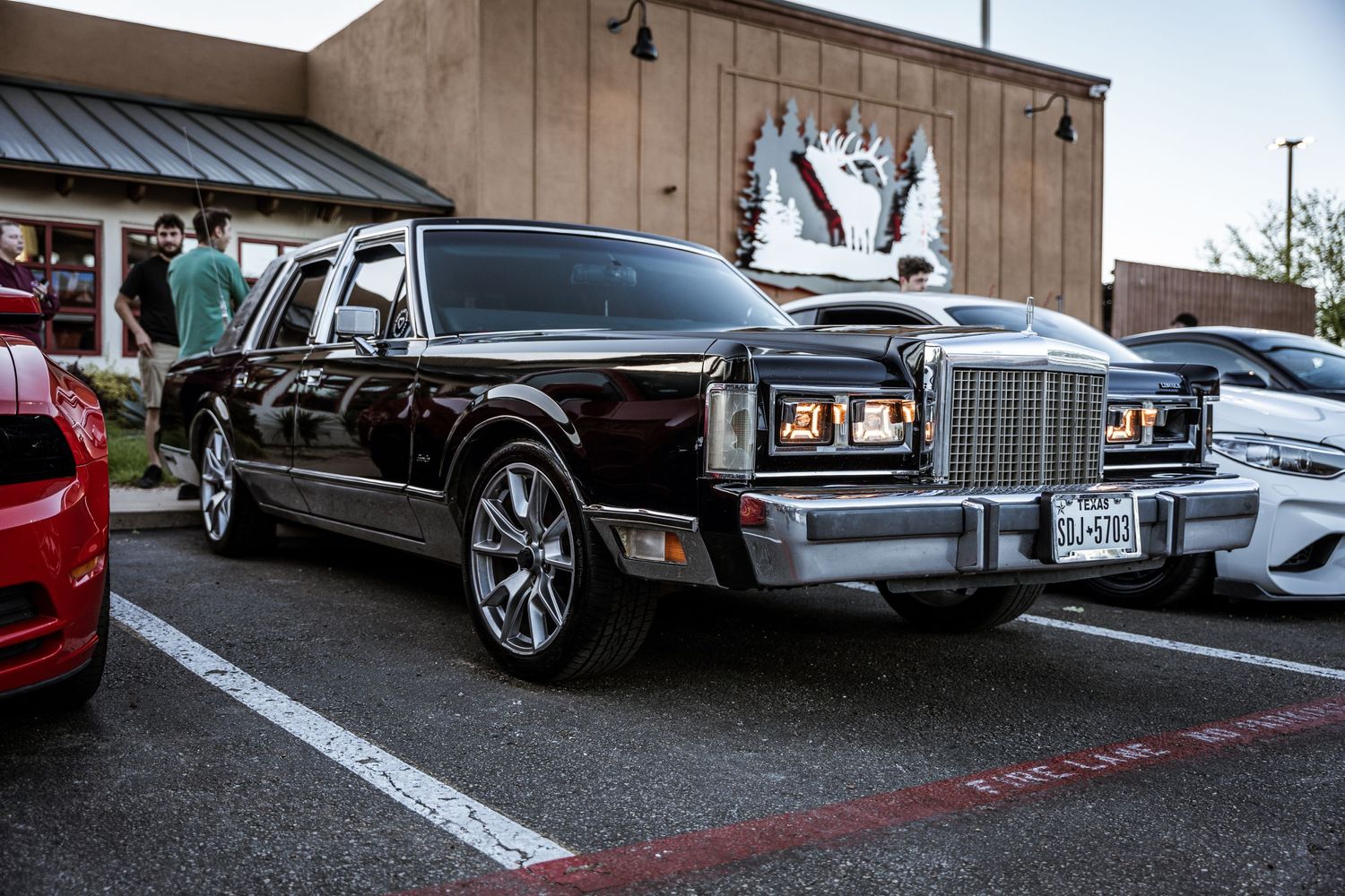Vintage black Lincoln Town Car customized with large wheels at a car show.