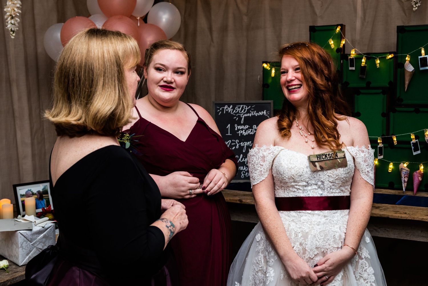 Wedding party members share a candid moment during reception celebrations while gathered around a bar area.