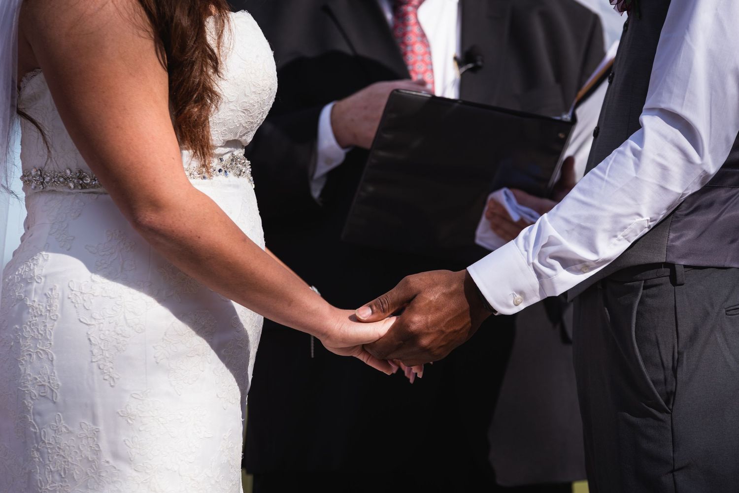 Close-up of hands joining during the wedding ceremony.
