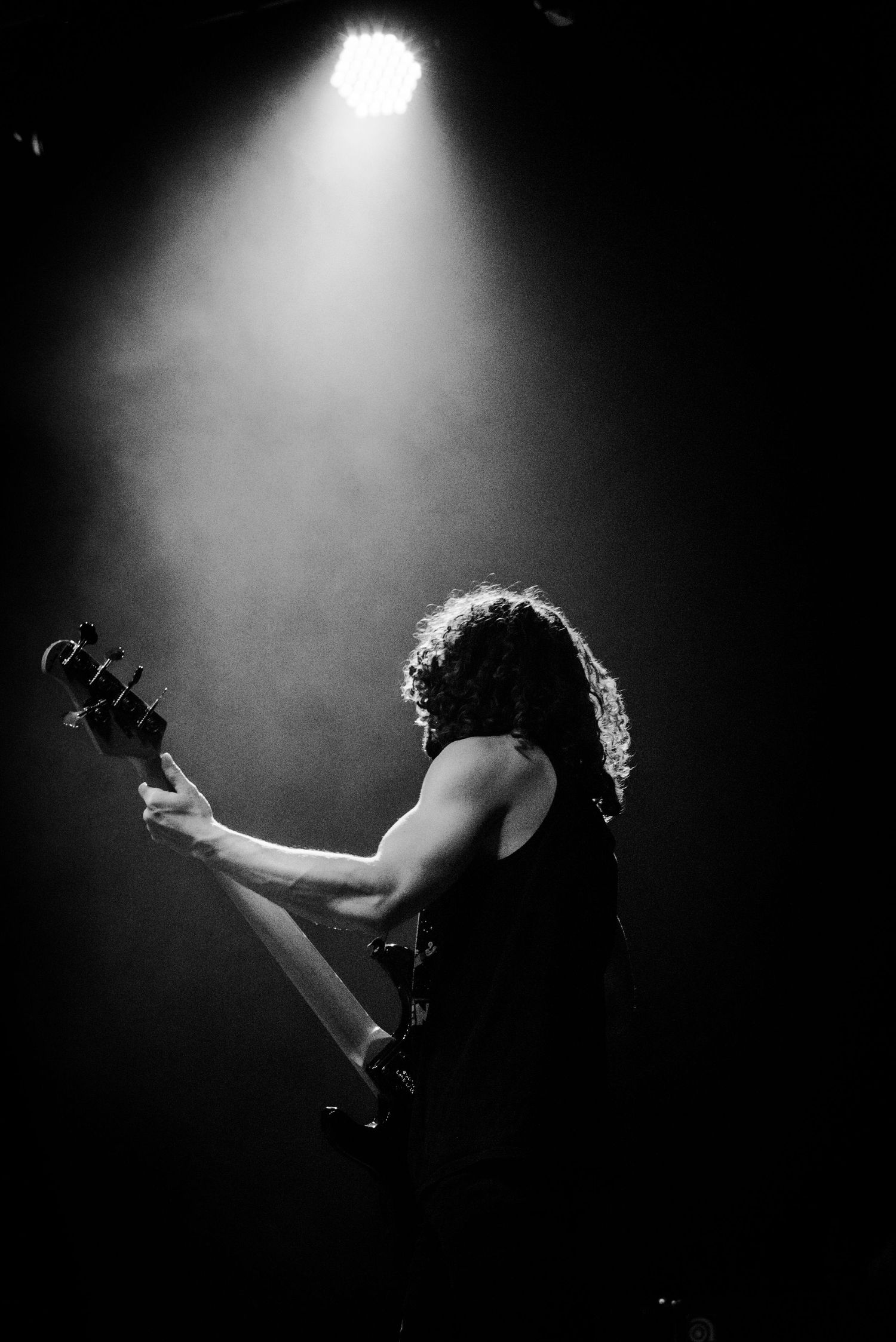 Dramatic black and white silhouette of guitarist performing under spotlight.