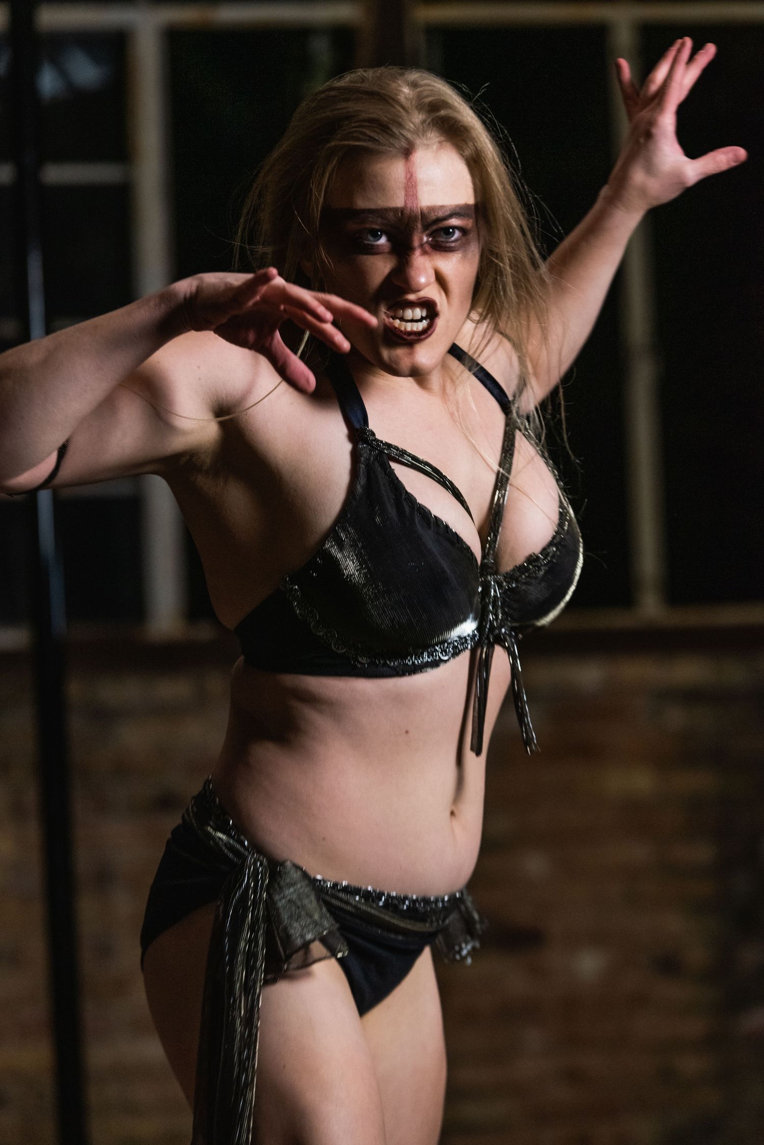 Dramatic performance art photo with expressive movement against brick wall backdrop.