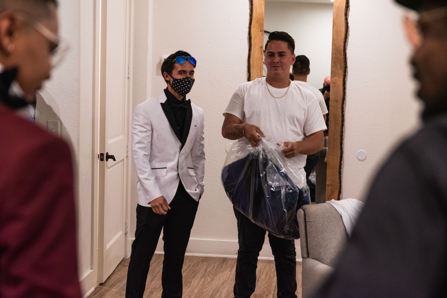 Wedding preparation scene with formal attire and face masks in white interior hallway.