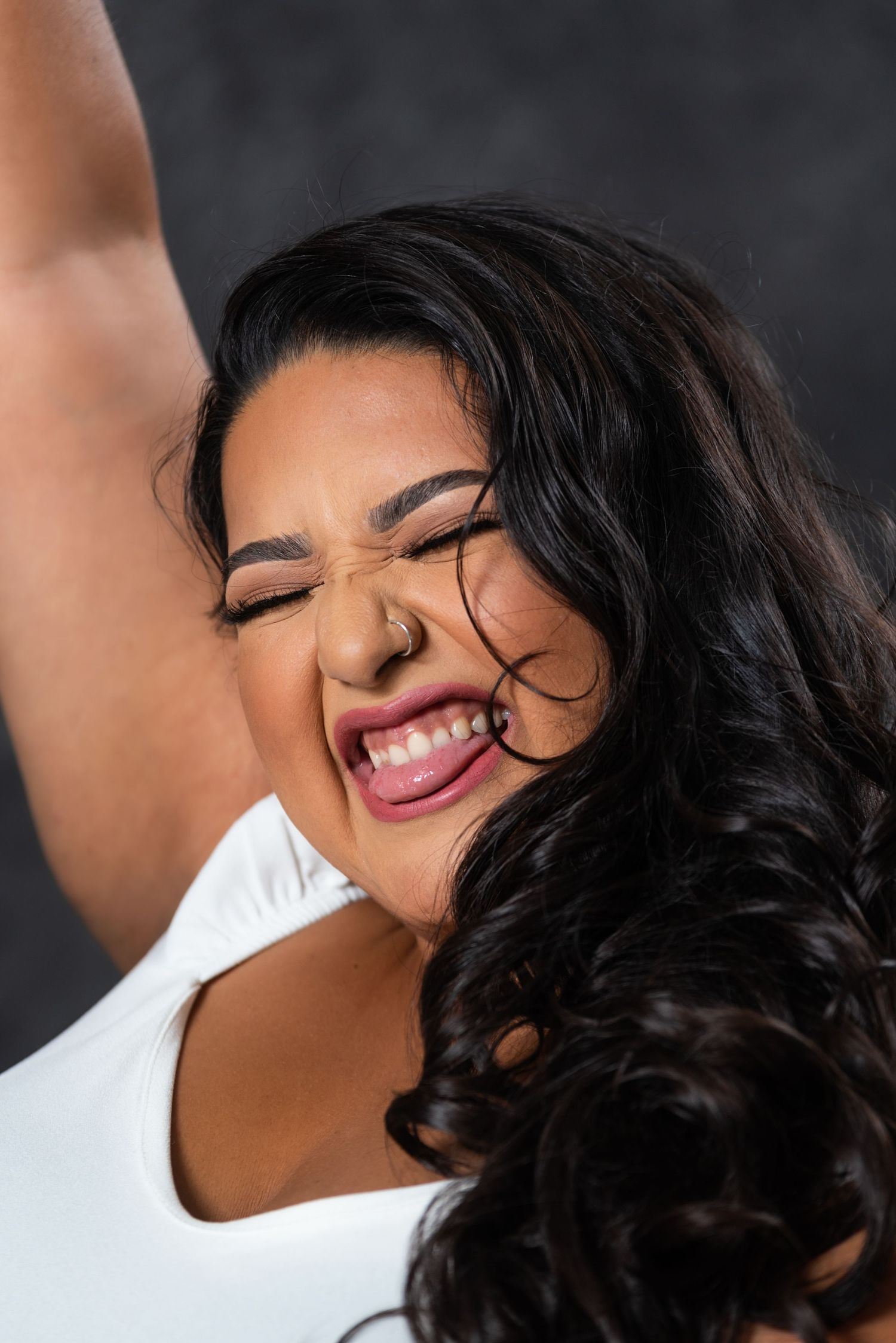 Joyful portrait with natural expression and flowing dark hair against dark backdrop.