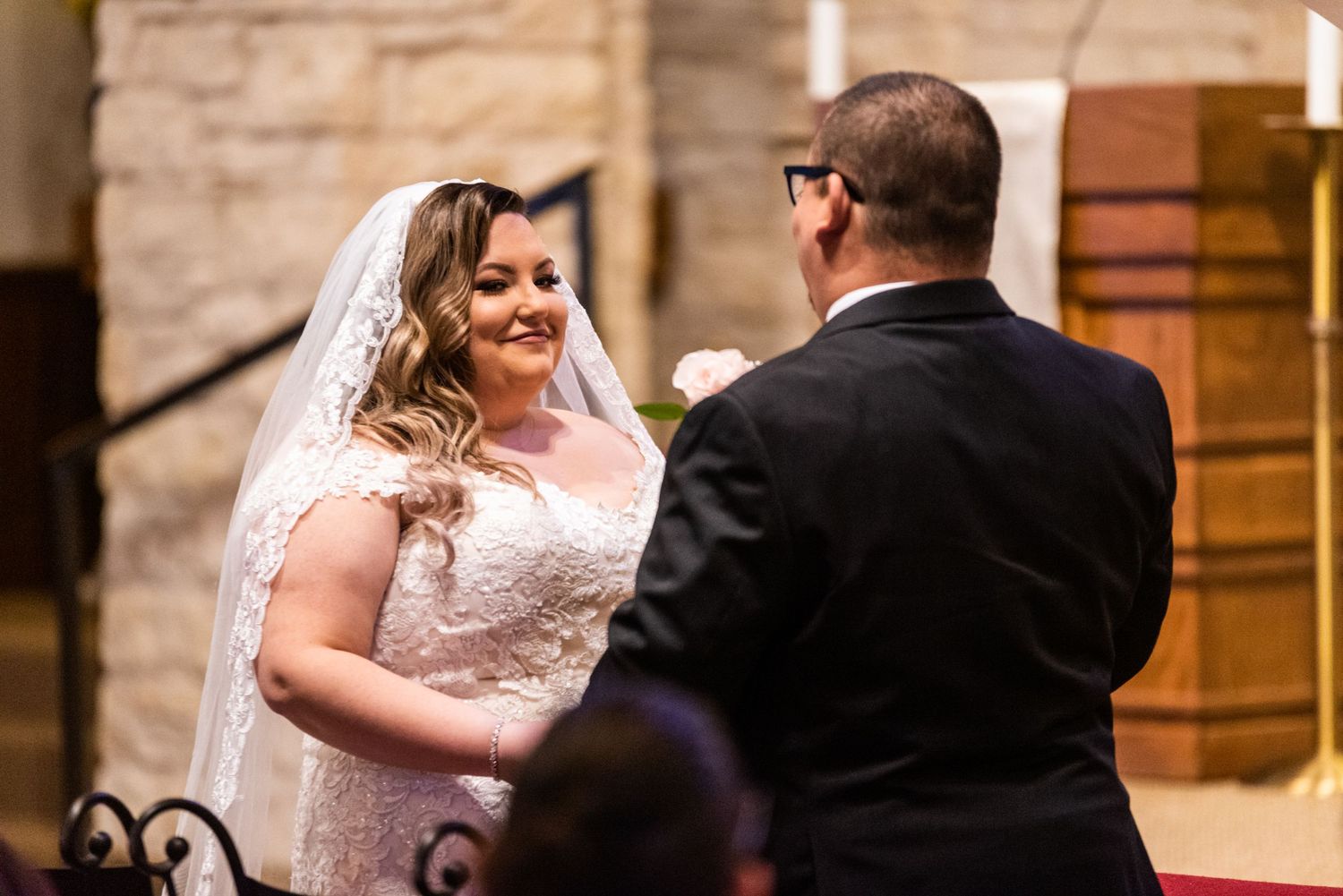 A couple exchanges vows during their wedding ceremony inside a stone church.