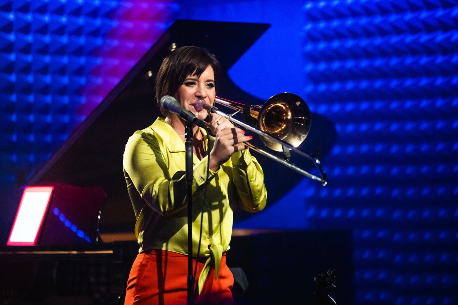 A musician performs with a trombone under blue stage lighting at Parker Jazz Club.