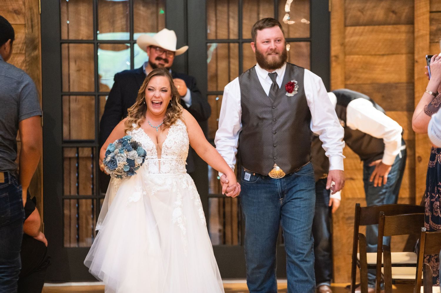 A joyful couple walking hand in hand during their rustic barn wedding celebration.