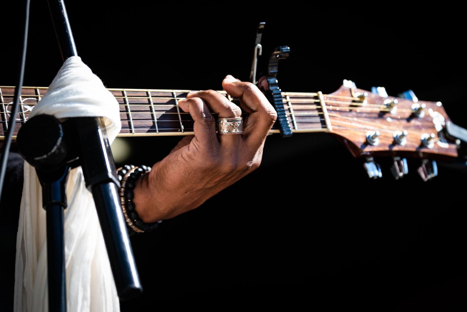 Close-up of a hand playing guitar chords on an acoustic guitar neck.