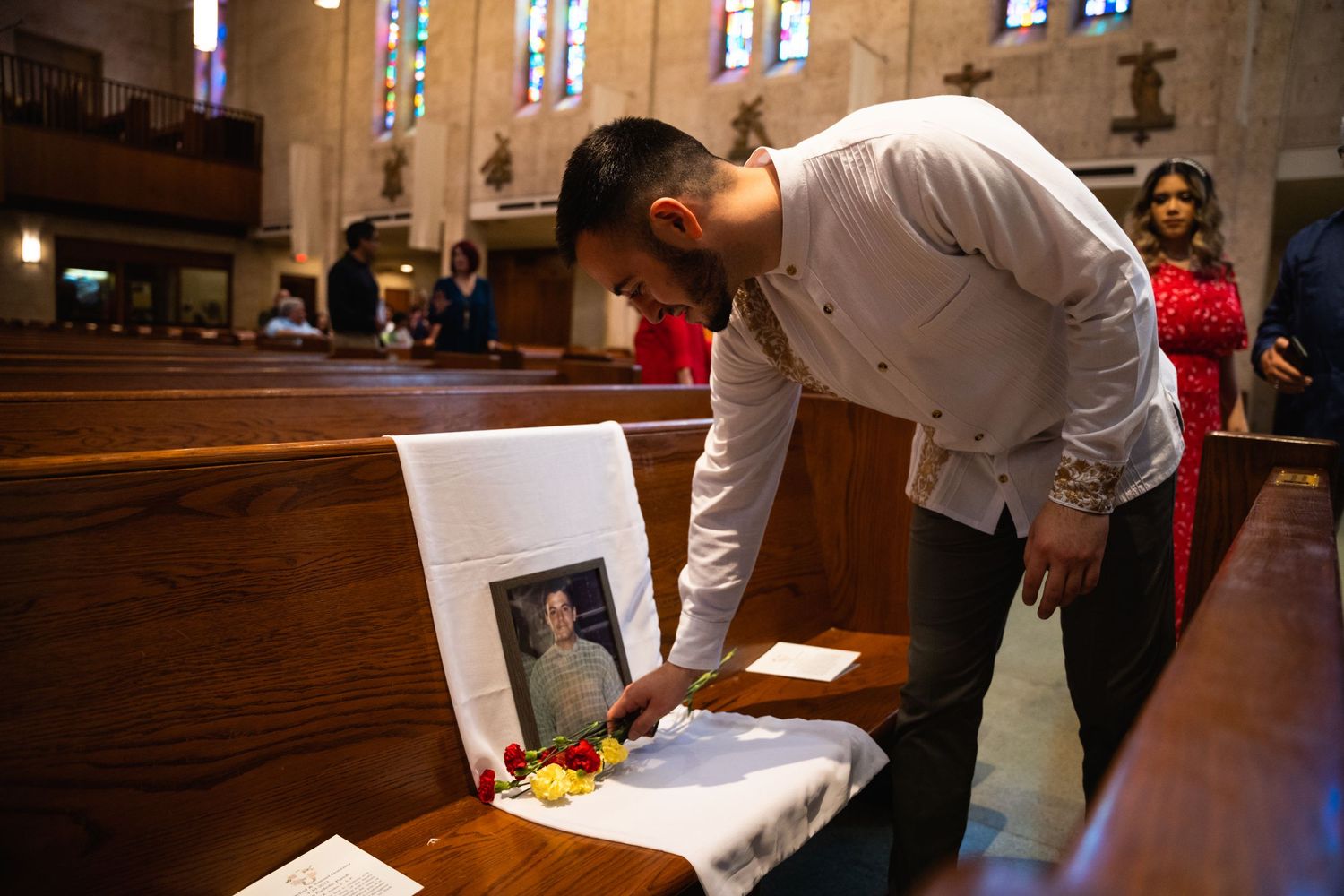 Person paying respects at a memorial display inside a church with stained glass windows.