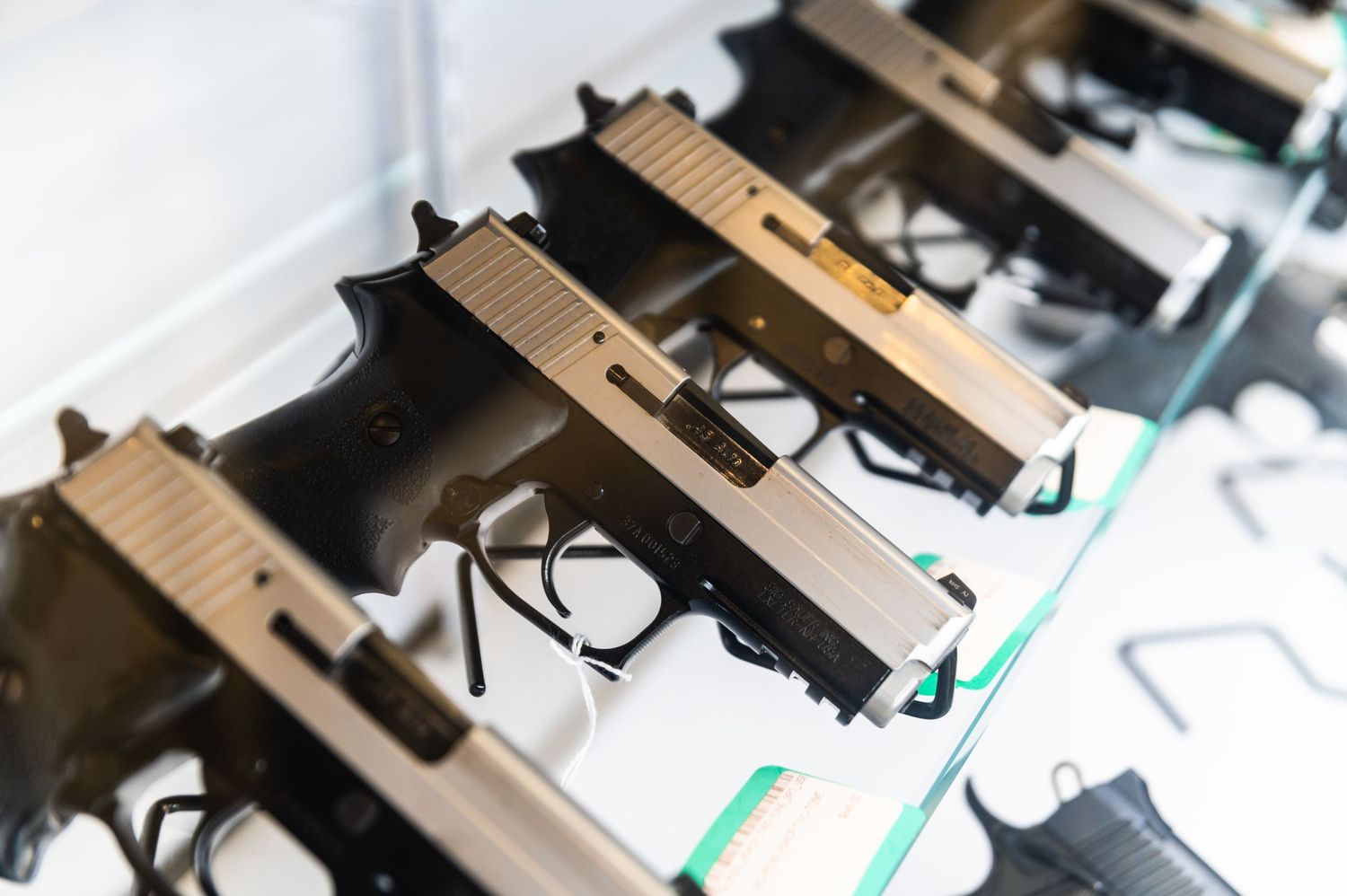 Row of identical handguns displayed on a glass counter at a shooting range.