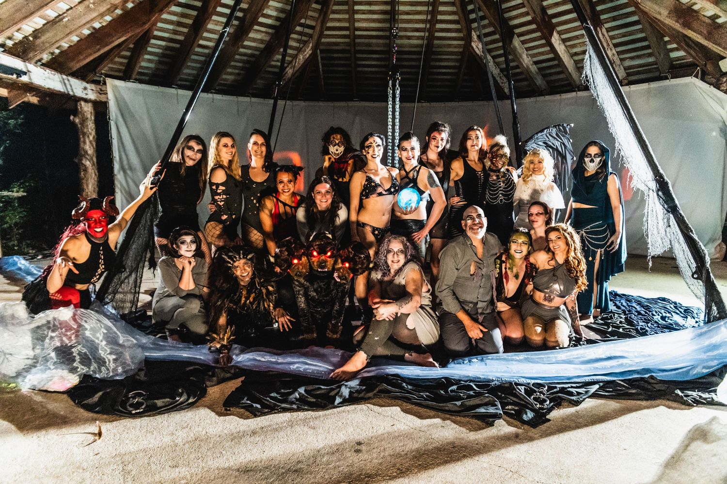 Large group gathered under a covered outdoor structure at a theatrical event.