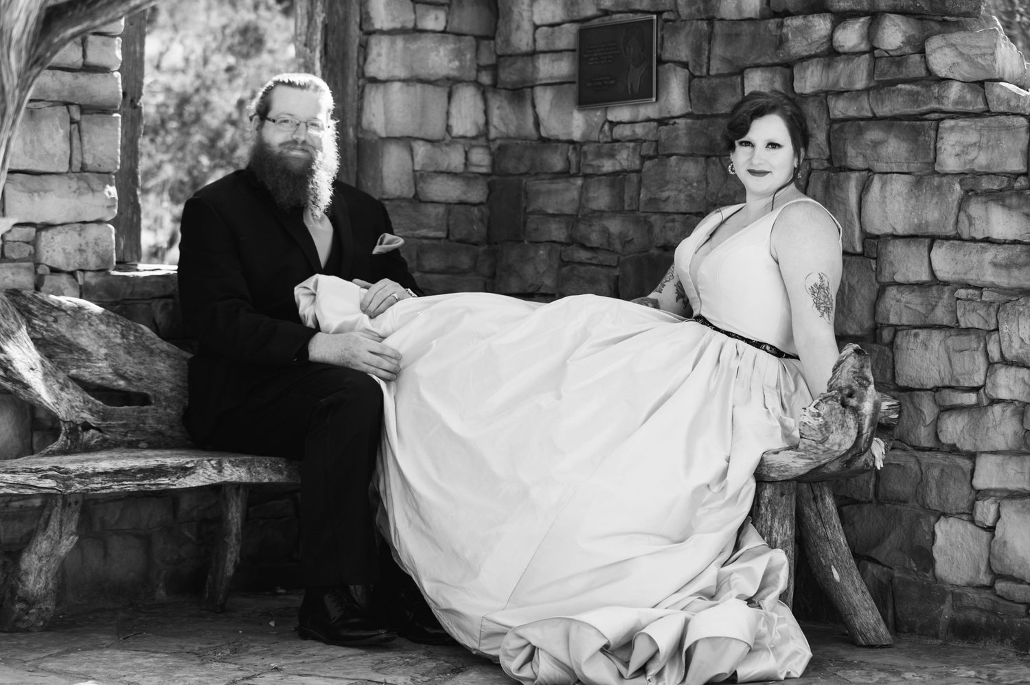 Black and white portrait of a couple sitting on stone steps in wedding attire.