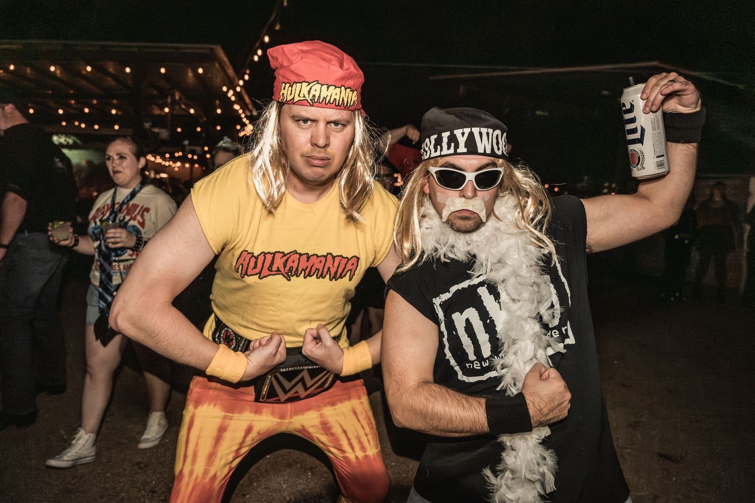 Party-goers in wrestling-themed costumes pose with drinks at a nighttime event.