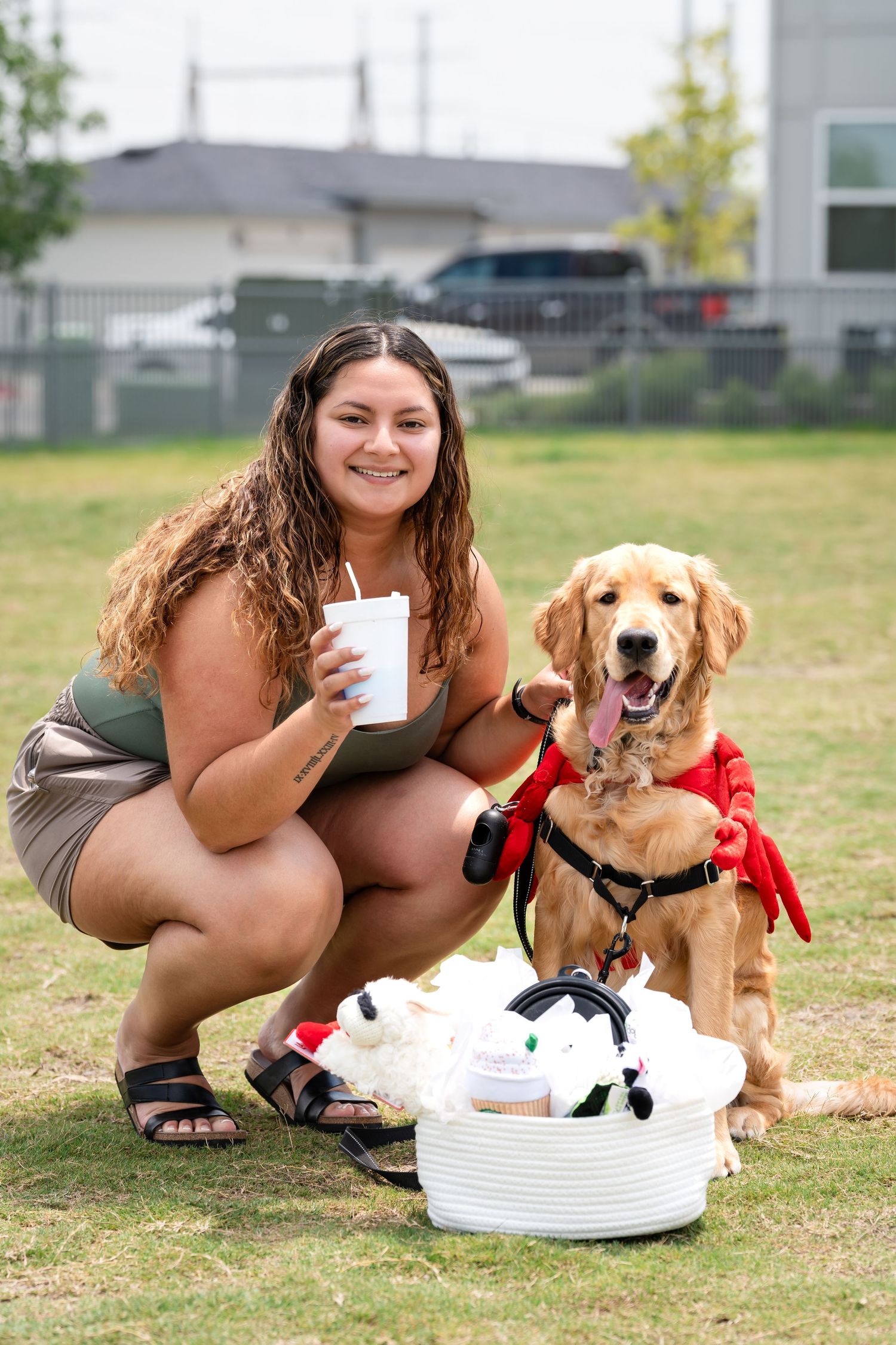 A Golden Retriever in a red bandana sits with their owner next to a basket of pet supplies.