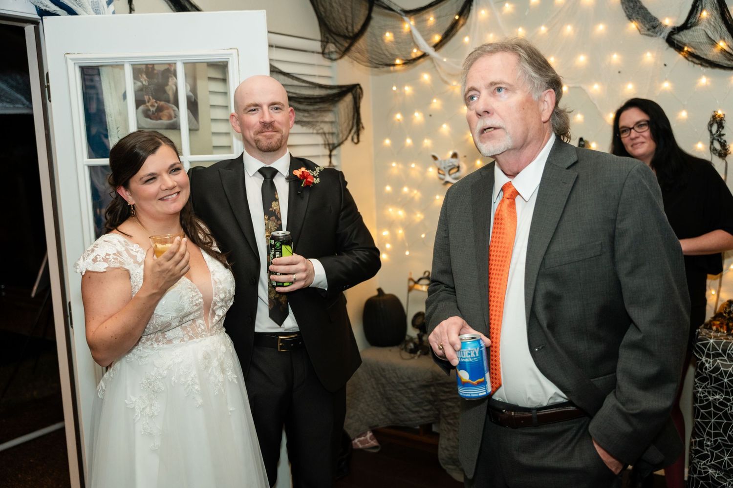 Candid moment of guests enjoying beverages at a wedding reception with fairy lights.