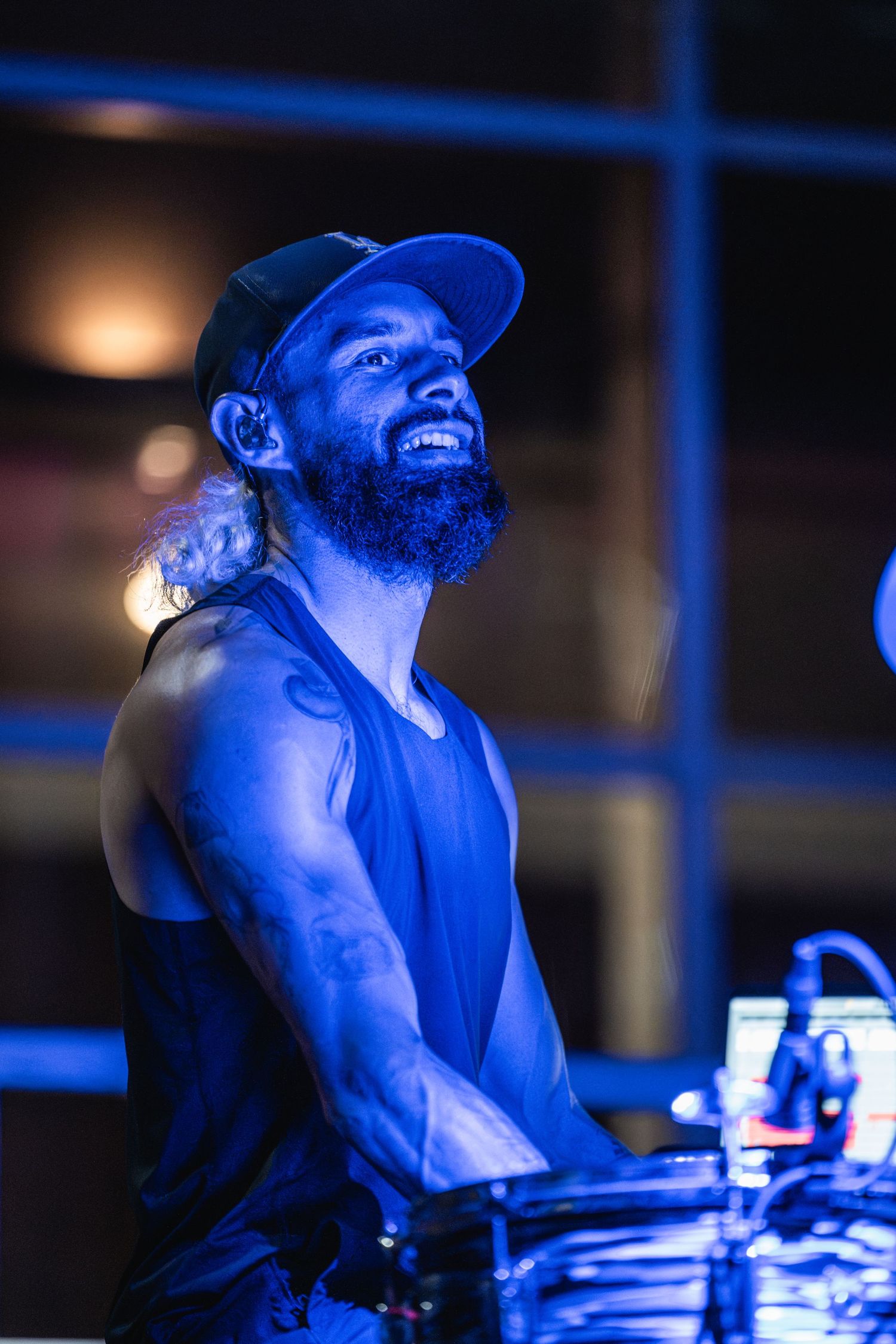 Drummer performing energetically under blue stage lighting at a concert.